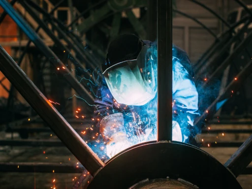 Welder working on metal structure as part of AMI industrial automation project in Latvia.