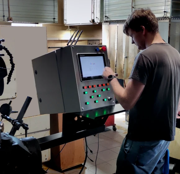 AMI engineer testing a custom industrial control panel with HMI interface in Latvia.
